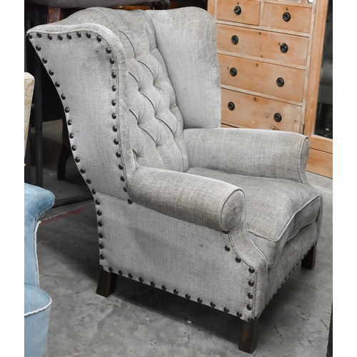 156 - A low-seated modern wing back armchair (reduced in height) upholstered in grey button back fabric wi... 