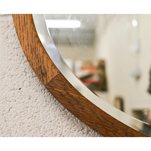 175 - A bevelled oval wall mirror in oak frame, 74 x 54 cm