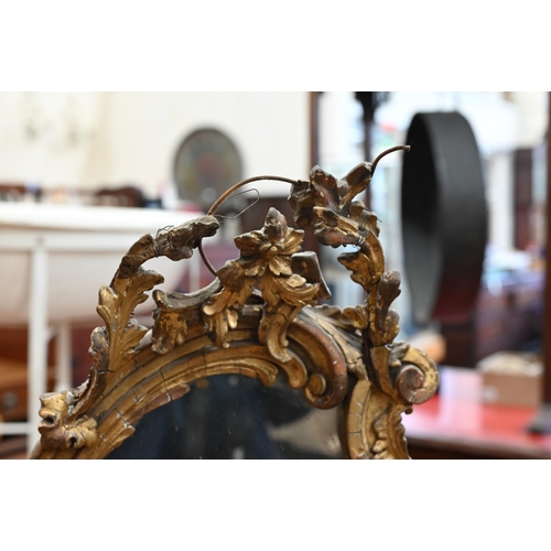 180 - An antique rococo mirror with giltwood and gesso floral and foliate frame and integrated shelf a/f, ... 