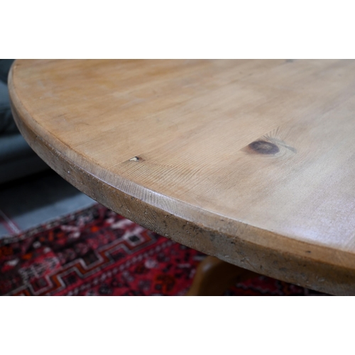 184 - A vintage circular pine dining table on turned column and triform supports, 134 cm diameter x 74 cm ... 