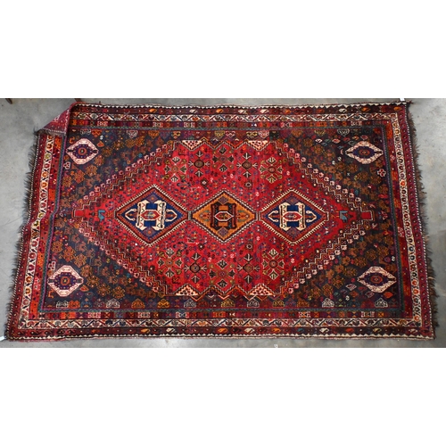 203 - A vintage Persian shiraz rug with triple lozenge medallion with floral and fauna design on red groun... 