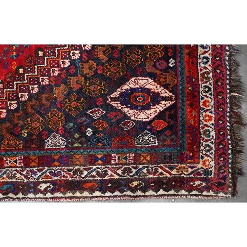 203 - A vintage Persian shiraz rug with triple lozenge medallion with floral and fauna design on red groun... 