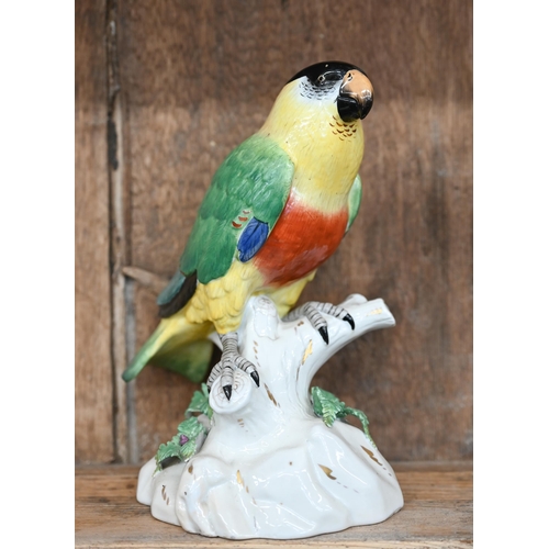 504 - A Continental porcelain model of a parrot perched on a branch, raised on a rocky base, underglaze 'R... 