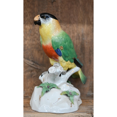 504 - A Continental porcelain model of a parrot perched on a branch, raised on a rocky base, underglaze 'R... 