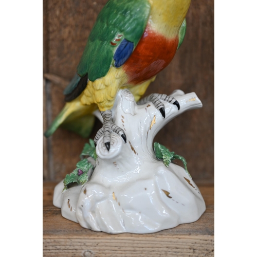 504 - A Continental porcelain model of a parrot perched on a branch, raised on a rocky base, underglaze 'R... 