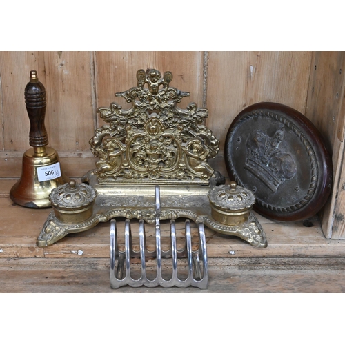 506 - An oval brass plaque cast with a Royal crown to/w a brass inkstand/stationery rack, a brass hand-bel... 