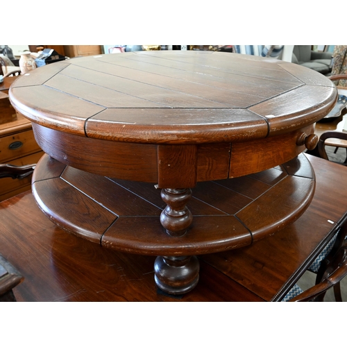 82 - A large stained oak circular coffee table with two drawers and open under-tier, raised on turned sup... 