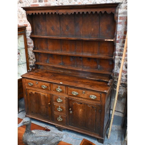 279 - An 18th century fruitwood and oak/elm dresser, the wavy cornice top with plank back over three shelv... 