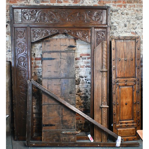 281 - A large architectural carved Indian hardwood door frame with a pair of associated doors and with an ... 