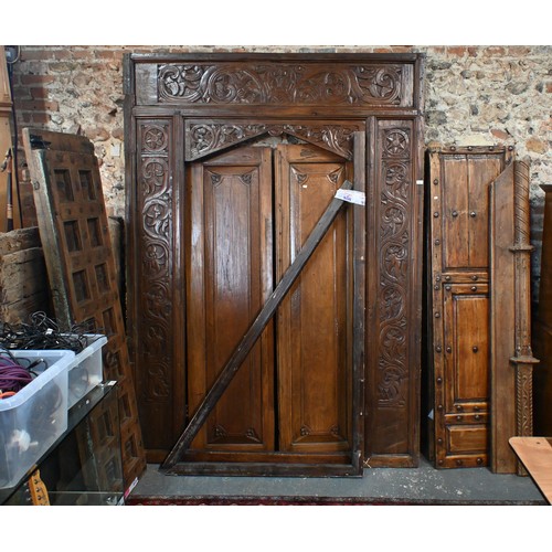 281 - A large architectural carved Indian hardwood door frame with a pair of associated doors and with an ... 