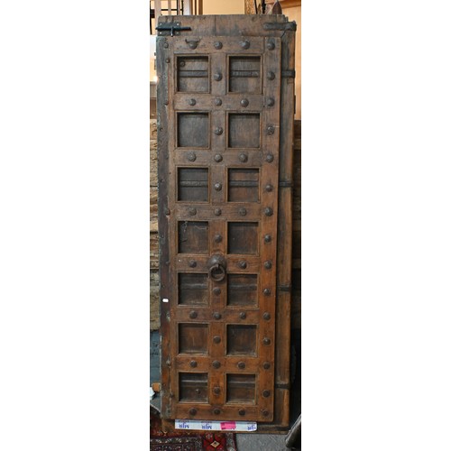 281 - A large architectural carved Indian hardwood door frame with a pair of associated doors and with an ... 