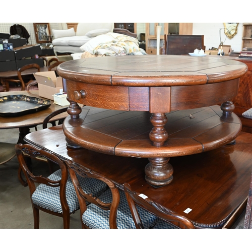 82 - A large stained oak circular coffee table with two drawers and open under-tier, raised on turned sup... 