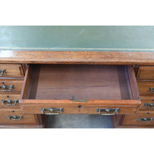 116 - A late 19th or early 20th century oak twin pedestal desk with gilt tooled green leather top over nin... 