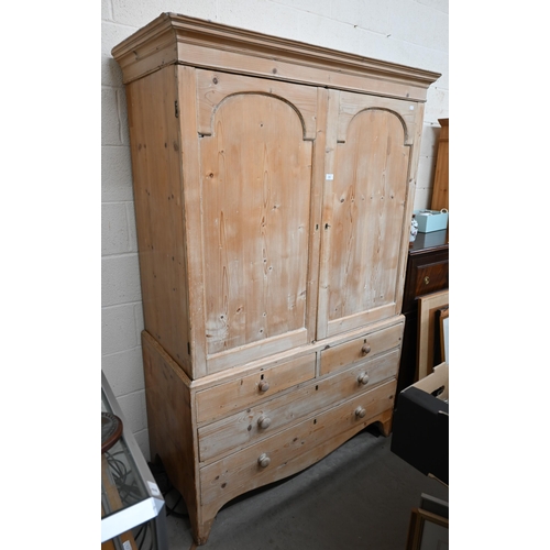 121 - A Victorian stripped pine linen press, the top section with moulded pediment over a pair of arched p... 