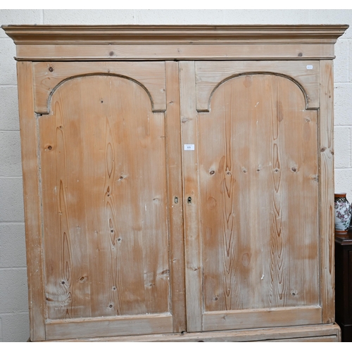 121 - A Victorian stripped pine linen press, the top section with moulded pediment over a pair of arched p... 