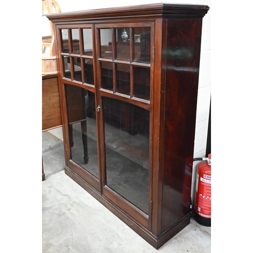 143 - An Edwardian mahogany library bookcase with two glazed doors enclosing three shelves, raised on plin... 