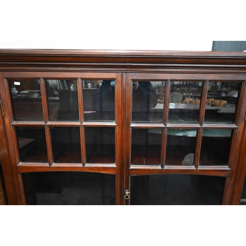 143 - An Edwardian mahogany library bookcase with two glazed doors enclosing three shelves, raised on plin... 