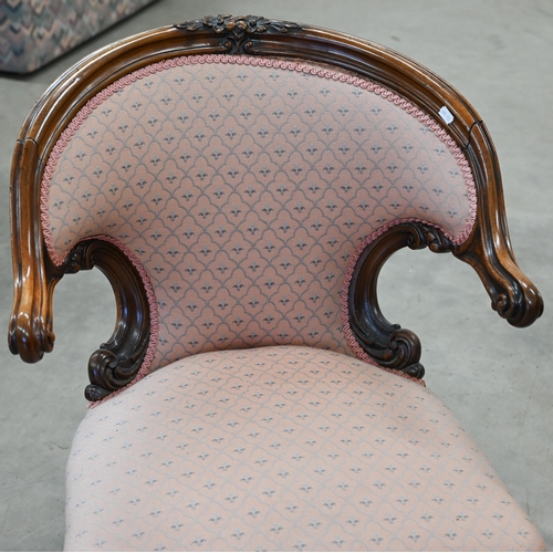 154 - A Victorian walnut framed nursing chair with floral carving, upholstered in pink fabric with repeati... 