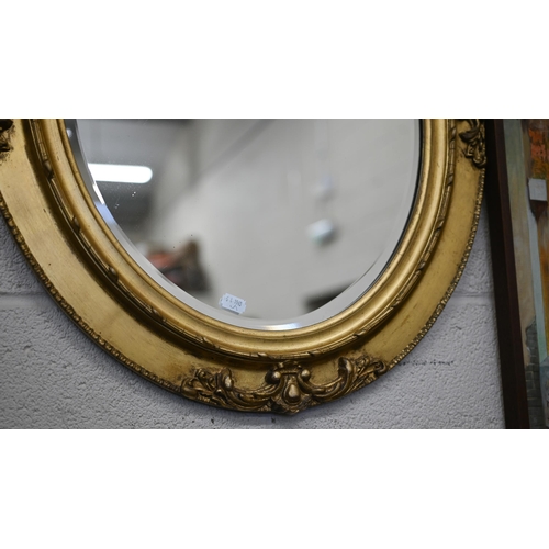 164 - A bevelled oval wall mirror in ornate gilt wood and gesso frame, 66 cm h x 55 cm w