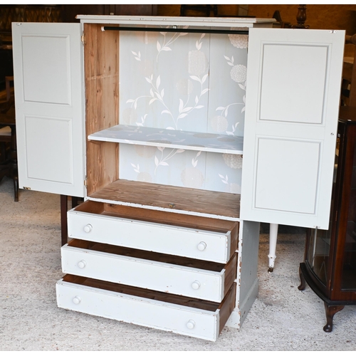 21 - A painted pine two door dwarf wardrobe with three long graduated drawers beneath, on a plinth base 9... 