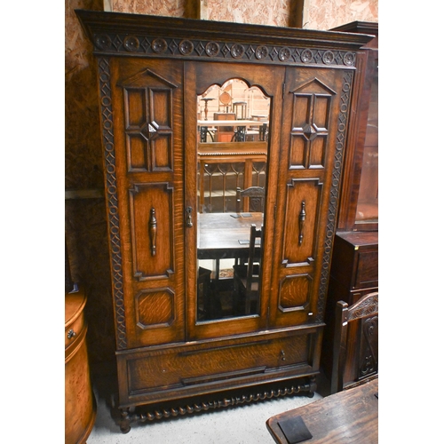 41 - An antique oak wardrobe, with single mirror panelled door flanked by moulded fixed panels, with full... 