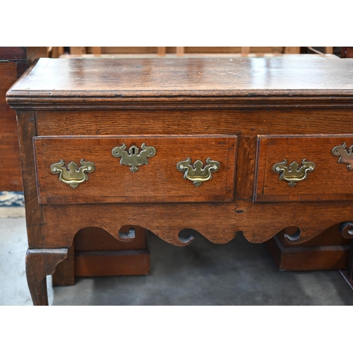 86 - A Georgian 18th century oak low dresser, the two drawers with brass handles over shaped fret-cut apr... 