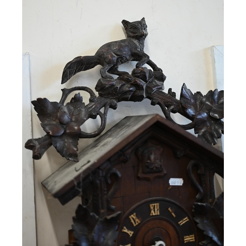 558 - A 20th century Black Forest style carved oak twin-weight cuckoo clock surmounted by a fox crest c/w ... 