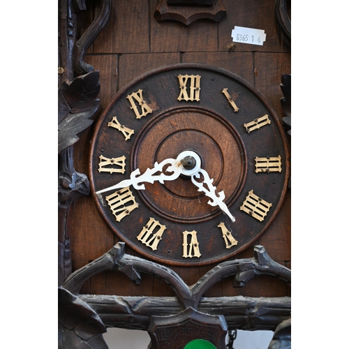 558 - A 20th century Black Forest style carved oak twin-weight cuckoo clock surmounted by a fox crest c/w ... 