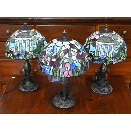 562 - A pair of Tiffany-style lamps with stained glass dome shades featuring cupolas, on Art Nouveau style... 