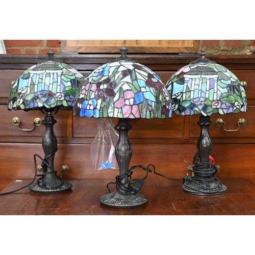 562 - A pair of Tiffany-style lamps with stained glass dome shades featuring cupolas, on Art Nouveau style... 