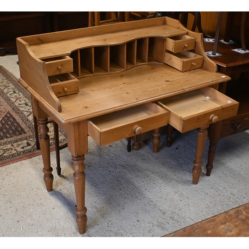 65 - A waxed pine desk with stationary racks/drawers, two frieze drawers and turned supports, 102 cm w x ... 