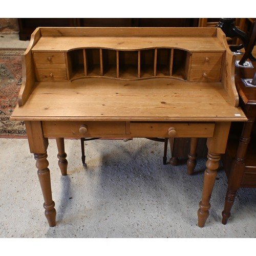 65 - A waxed pine desk with stationary racks/drawers, two frieze drawers and turned supports, 102 cm w x ... 