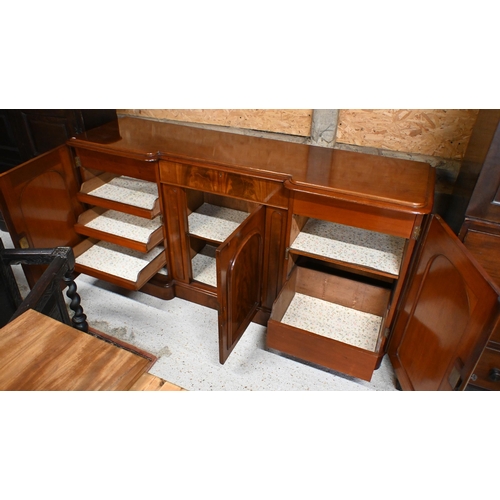 165 - A Victorian figured mahogany inverted breakfront sideboard with central drawer and arch panelled cup... 