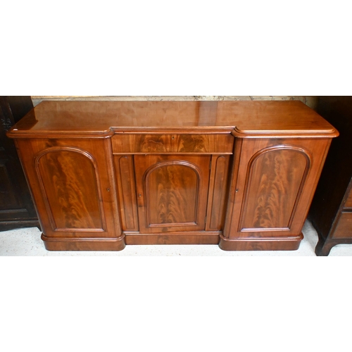 165 - A Victorian figured mahogany inverted breakfront sideboard with central drawer and arch panelled cup... 