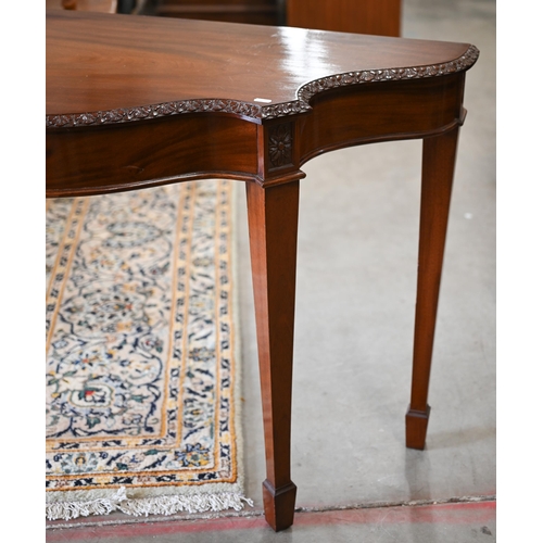 202 - A reproduction carved mahogany serpentine console table on tapering square supports with spade feet,... 