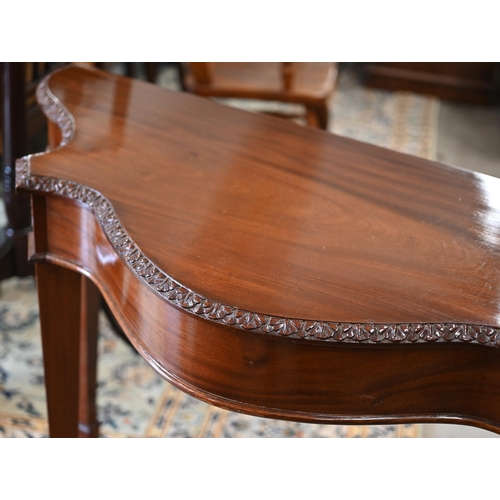 202 - A reproduction carved mahogany serpentine console table on tapering square supports with spade feet,... 