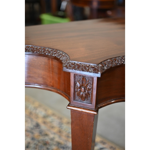 202 - A reproduction carved mahogany serpentine console table on tapering square supports with spade feet,... 