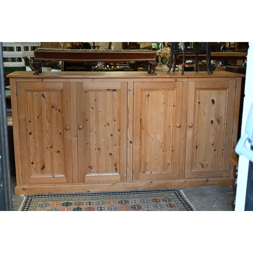 203 - A vintage stained pine pantry cupboard with two pairs of panelled cupboard doors enclosing shelved i... 