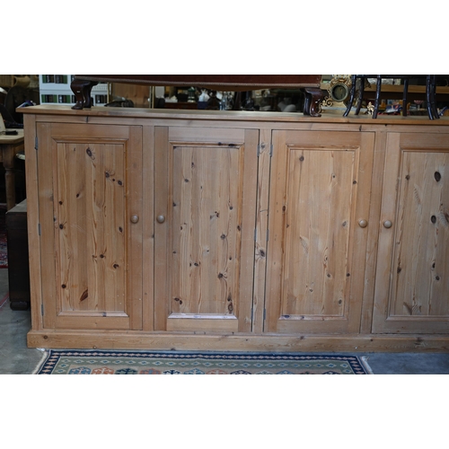 203 - A vintage stained pine pantry cupboard with two pairs of panelled cupboard doors enclosing shelved i... 