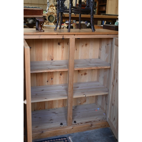 203 - A vintage stained pine pantry cupboard with two pairs of panelled cupboard doors enclosing shelved i... 