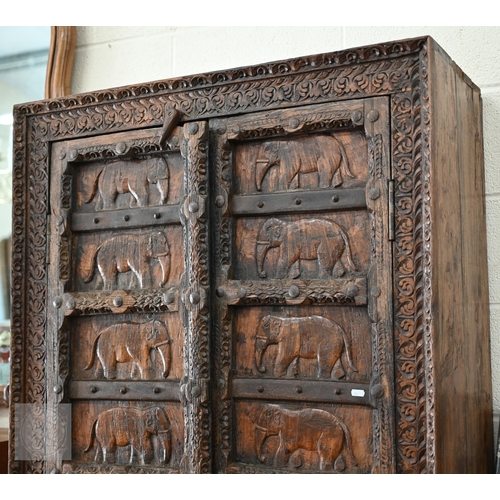 253 - Indian stained hardwood 'Havali' cupboard profusely carved with foliate designs around the frame and... 