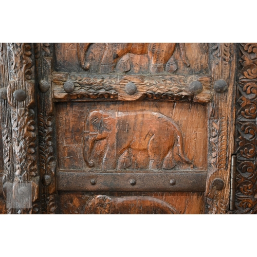 253 - Indian stained hardwood 'Havali' cupboard profusely carved with foliate designs around the frame and... 