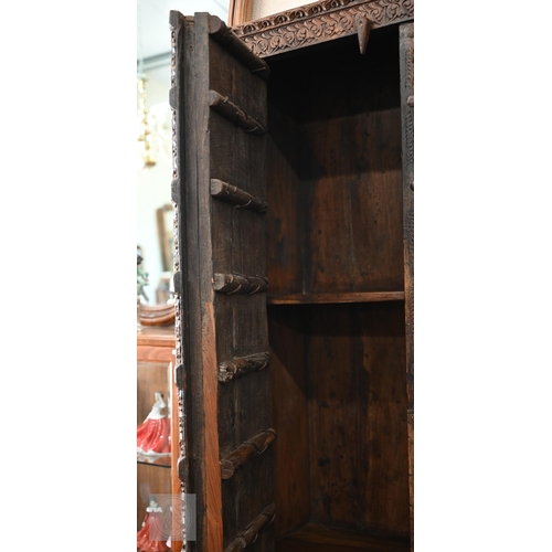 253 - Indian stained hardwood 'Havali' cupboard profusely carved with foliate designs around the frame and... 