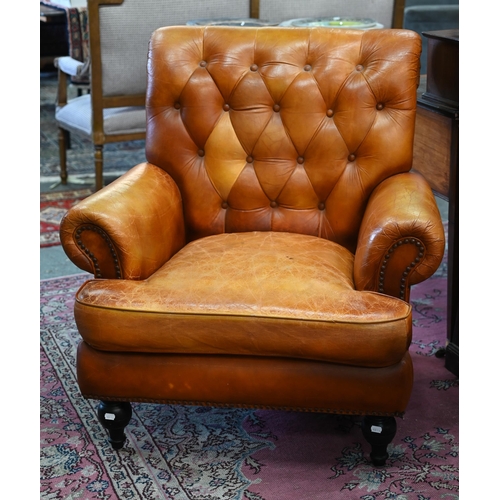 268 - A Victorian style tan leather button backed armchair, raised on turned front legs, uneven colour fad... 