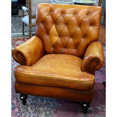 268 - A Victorian style tan leather button backed armchair, raised on turned front legs, uneven colour fad... 