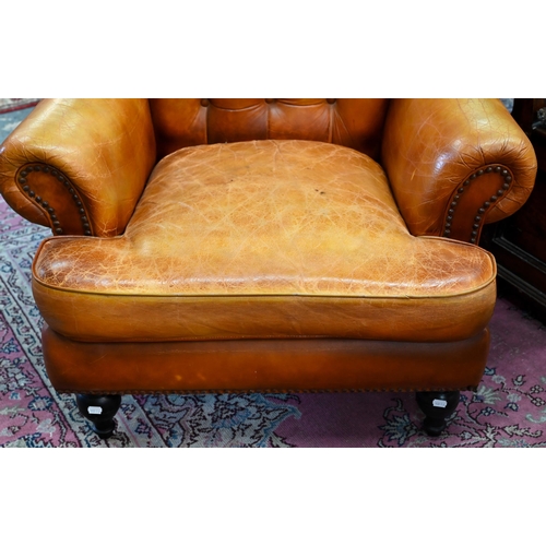 268 - A Victorian style tan leather button backed armchair, raised on turned front legs, uneven colour fad... 