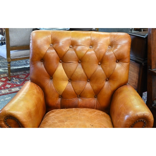 268 - A Victorian style tan leather button backed armchair, raised on turned front legs, uneven colour fad... 