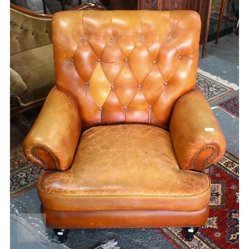 268 - A Victorian style tan leather button backed armchair, raised on turned front legs, uneven colour fad... 