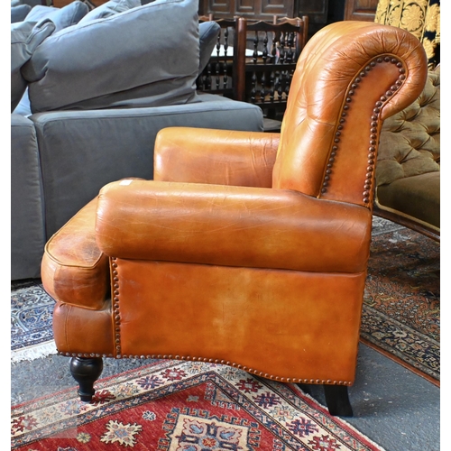 268 - A Victorian style tan leather button backed armchair, raised on turned front legs, uneven colour fad... 