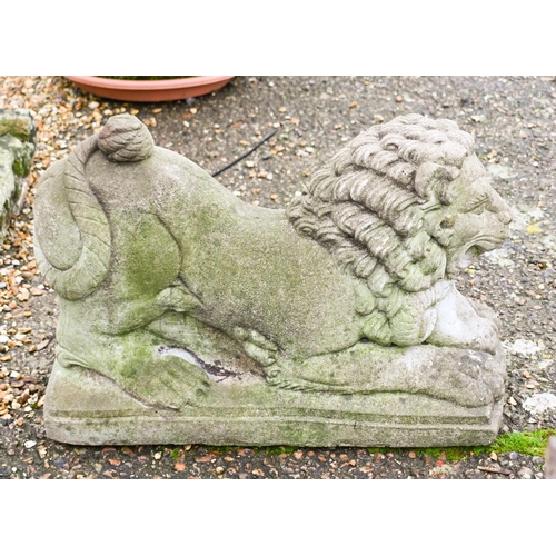 5 - A weathered cast stone garden statue of a recumbent lion